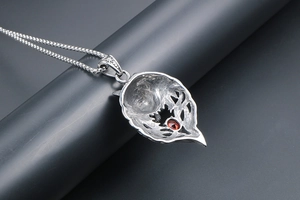 Close-up of silver titanium steel fox pendant featuring a red zircon and hollow carving