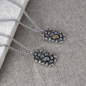 Detail of vintage punk skull pendants in silver and gold tones on a metal woven chain