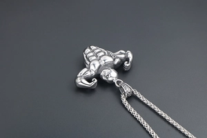 Macro shot of silver titanium steel necklace featuring a muscular male body pendant
