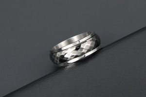 Macro detail of men's rotatable spinner ring with hammered texture and brushed steel finish