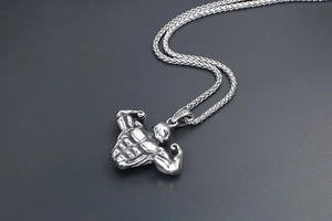 Detail of silver titanium steel fitness pendant with muscular torso and wheat chain