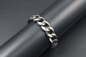 Close-up of a heavy polished silver-tone curb chain bracelet on a black display stand