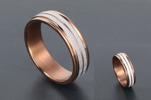 Macro detail of rose gold titanium ring featuring dual silver brushed metal inlay bands