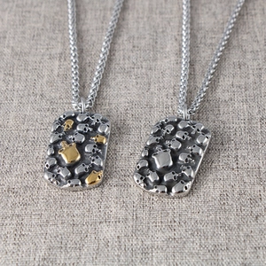 Detail of gothic punk dog tag pendants with 3D embossed skulls in silver and gold finish