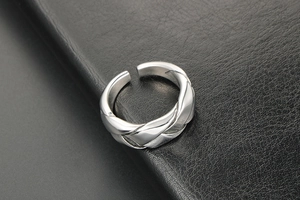 Detail of woven texture on silver stainless steel ring over dark leather background