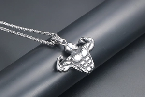 Detail view of silver bodybuilding pendant showing muscular texture and steel chain