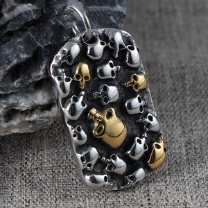 Macro view of punk rectangle pendant with silver and gold skull relief on dark metal