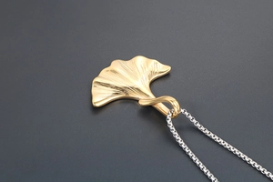 Macro del ciondolo a foglia di ginkgo dorata con venature su catena in argento fine