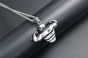 Macro detail of silver muscular bodybuilder pendant on thick wheat chain necklace