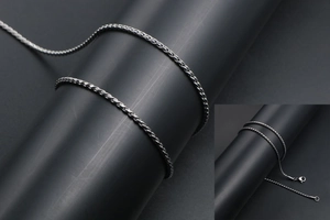 Macro detail of polished stainless steel wheat chain necklace with intricate braided texture