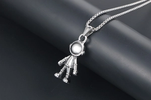 Gros plan détaillé d'un pendentif astronaute en argent avec design robotique sur sa chaîne
