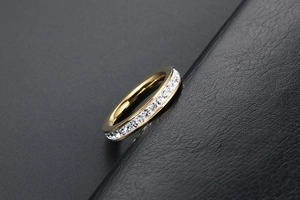Primo piano di un anello eternity in oro rosa con zirconi su superficie in pelle nera