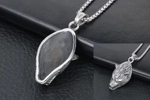 Close-up of a carved wolf head pendant in silver titanium steel with a square pearl chain