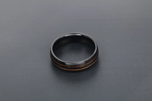 Gros plan détaillé d'une bague en titane noir poli avec deux inserts en grain de bois brun
