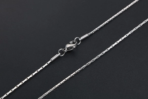 Detailed close-up of a minimalist stainless steel chain with a secure lobster clasp