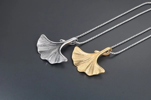 Dettaglio macro dei ciondoli a foglia di ginkgo oro e argento con trame venate fini