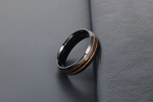 Détail de la bague en acier titane avec bords noirs et incrustation en bois de noyer