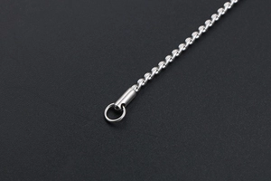Macro detail of silver twisted rope chain with cylindrical clasp on black background