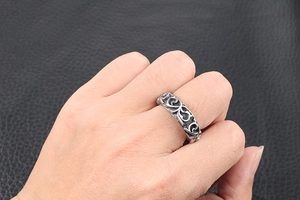 Detailed view of retro steel ring featuring engraved floral scroll patterns on finger