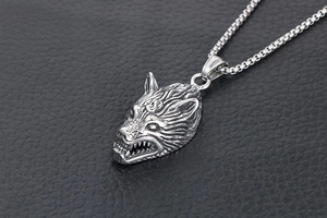 Detailed view of wolf head pendant in vintage steel on black leather background