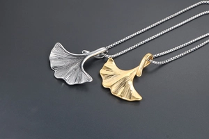 Dettaglio dei ciondoli a forma di foglia di ginkgo in oro e argento con venature