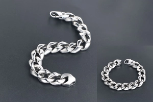 Détail de bracelet à maille gourmette argentée avec fermoir mousqueton sur fond gris
