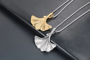 Dettaglio ravvicinato di ciondoli a foglia di ginkgo in oro e argento con venature