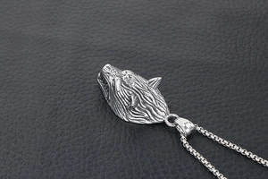 Detailed macro view of a silver wolf head pendant with intricate fur texture and box chain