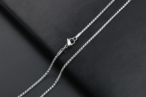 Close-up of a silver titanium steel rope chain necklace with a lobster clasp on black leather