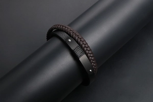 Détail d'un bracelet en cuir multicouche avec plaque en métal noir et clous argentés
