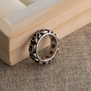 Vintage titanium steel ring with gothic floral engravings on a wooden tray