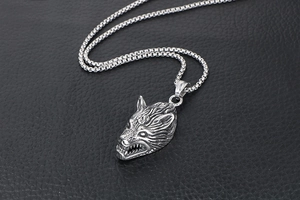 Macro shot of a vintage wolf head pendant in silver titanium steel on black leather
