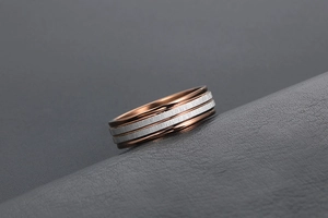 Macro shot of two-tone titanium ring with silver brushed bands and rose gold polished base