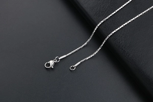 Macro shot of silver stainless steel chain with lobster clasp and faceted link detail