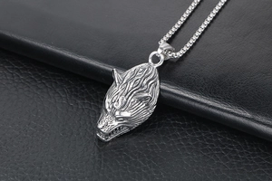 Detailed macro shot of vintage wolf head pendant in titanium steel on black leather
