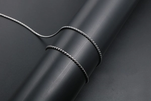 Detailed view of woven titanium steel twist chain with dark metallic finish and texture