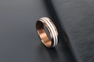Close-up of rose gold and silver brushed steel ring band with contrasting textures