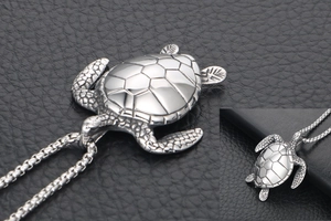 Macro shot of silver turtle pendant with detailed shell texture on black leather background