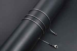 Detailed view of silver-black faceted steel necklace with lobster clasp on display