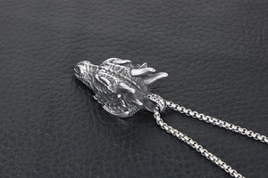 Gros plan du pendentif tête de dragon en argent vieilli avec détails sur cuir noir