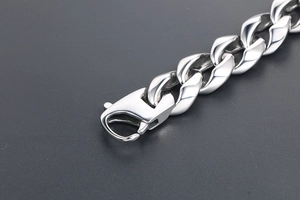 Gros plan sur un bracelet gourmette en acier titane avec fermoir mousqueton et fini miroir
