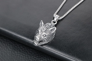Detailed view of carved wolf head pendant in silver titanium steel on black leather