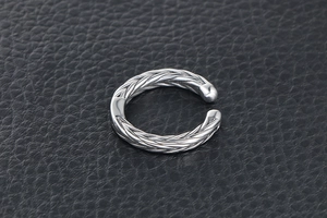 Macro shot of silver wheat ear pattern on a titanium steel open ring on leather