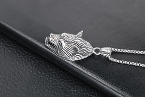 Detail of a fierce silver wolf head pendant with textured fur and polished box chain