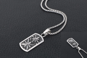 Detail of vintage steel military dog tag necklace with engraved octagonal stars on black leather
