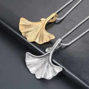 Collane con pendente a foglia di ginkgo oro e argento su sfondo di pelle nera