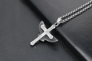 Vue détaillée du pendentif croix punk et aile d'aigle sur fond de cuir noir texturé