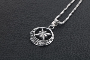 Macro view of vintage stainless steel compass pendant with Celtic knot on black leather