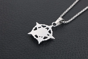 Macro shot of silver compass star pendant necklace on black textured leather surface