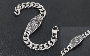 Macro detail of punk curb chain bracelet with engraved star flower motif on steel